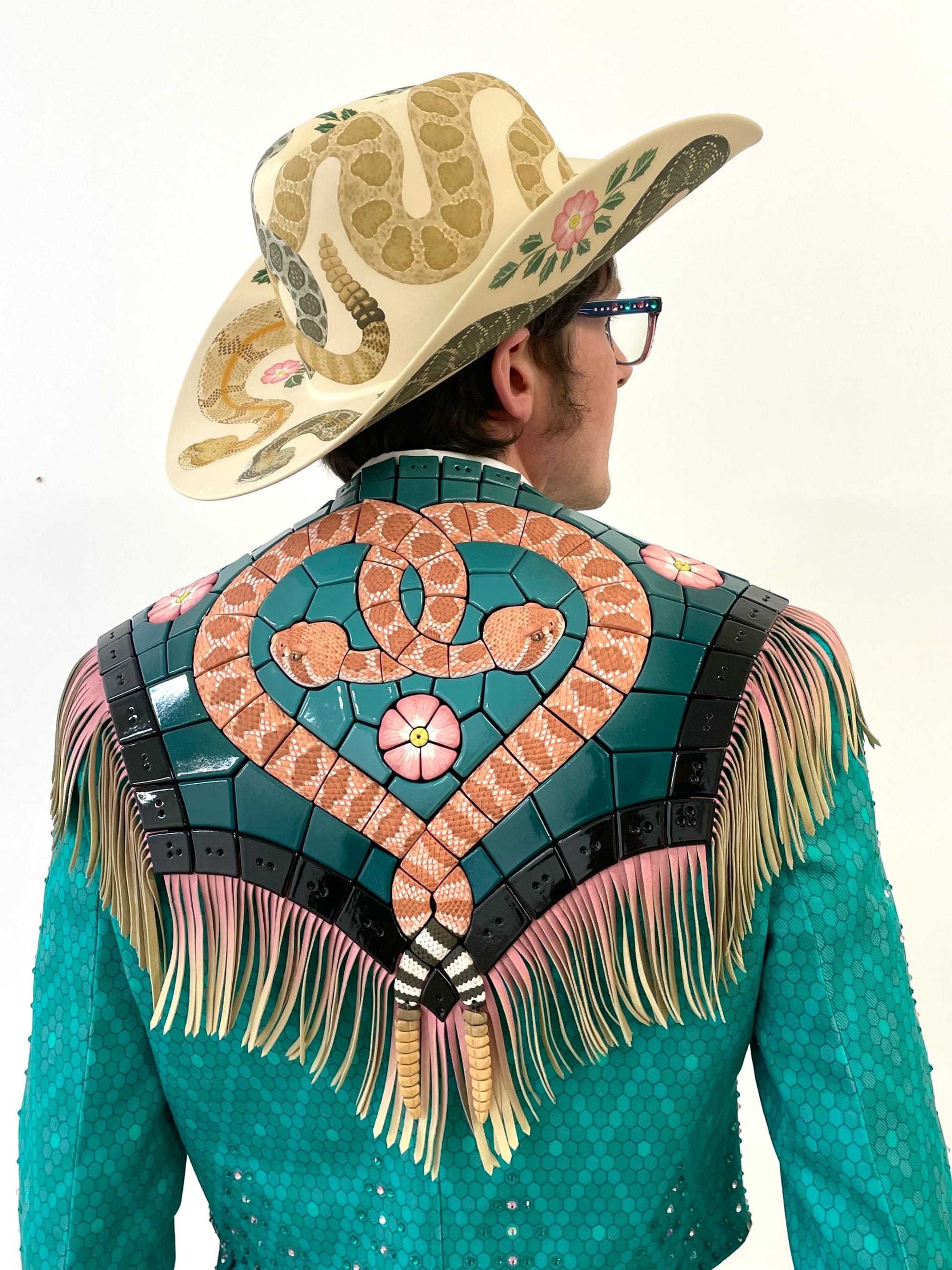 Shae Bishop wears a fringed suit and cowboy hat with elaborate tiles featuring snakes