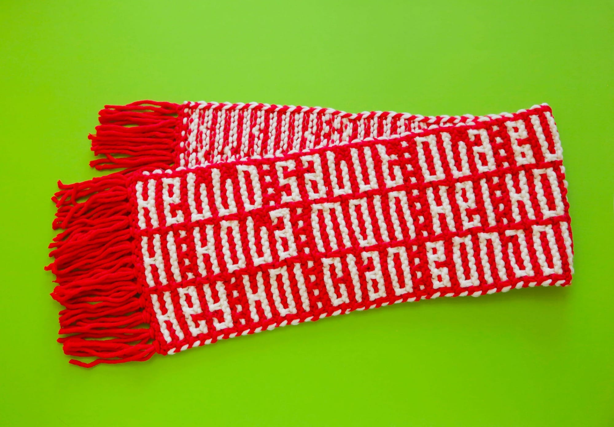 a knitted red-and-white scarf with the word "HELLO" in numerous languages