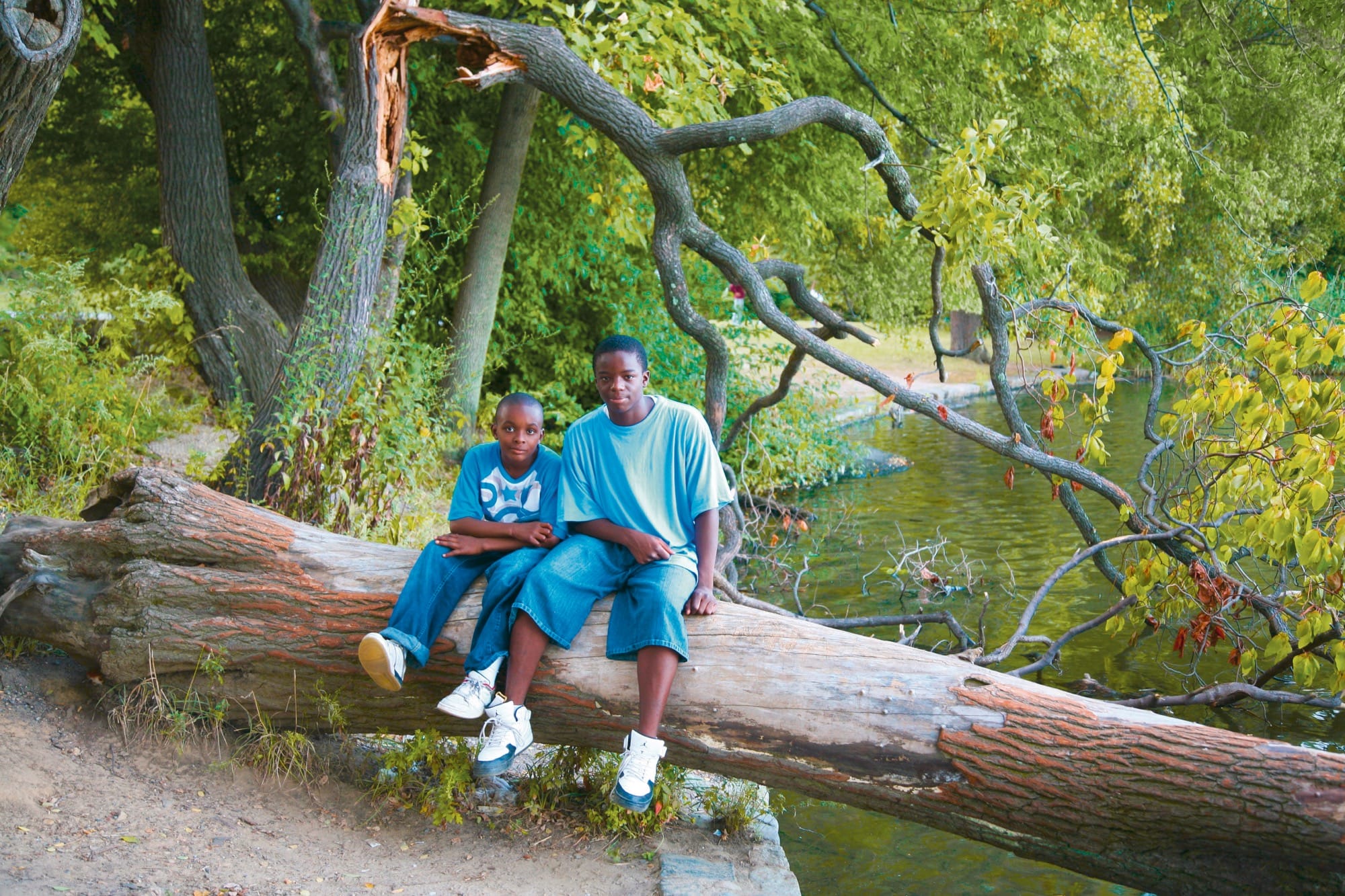 a photo by Jamel Shabbaz of two boys sitting on a log