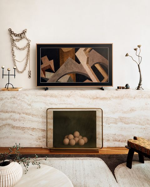 The false fireplace in Adam’s living room was constructed by carpenter Trevor Miles, then wrapped in travertine-style wallpaper from Belarte.