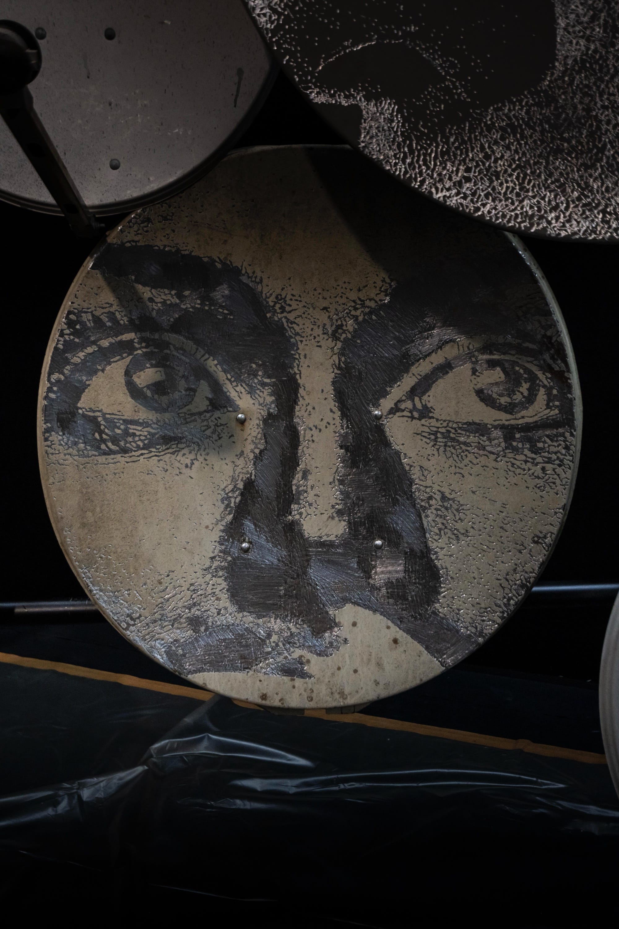 a detail of a face painted on a circular form by Vhils