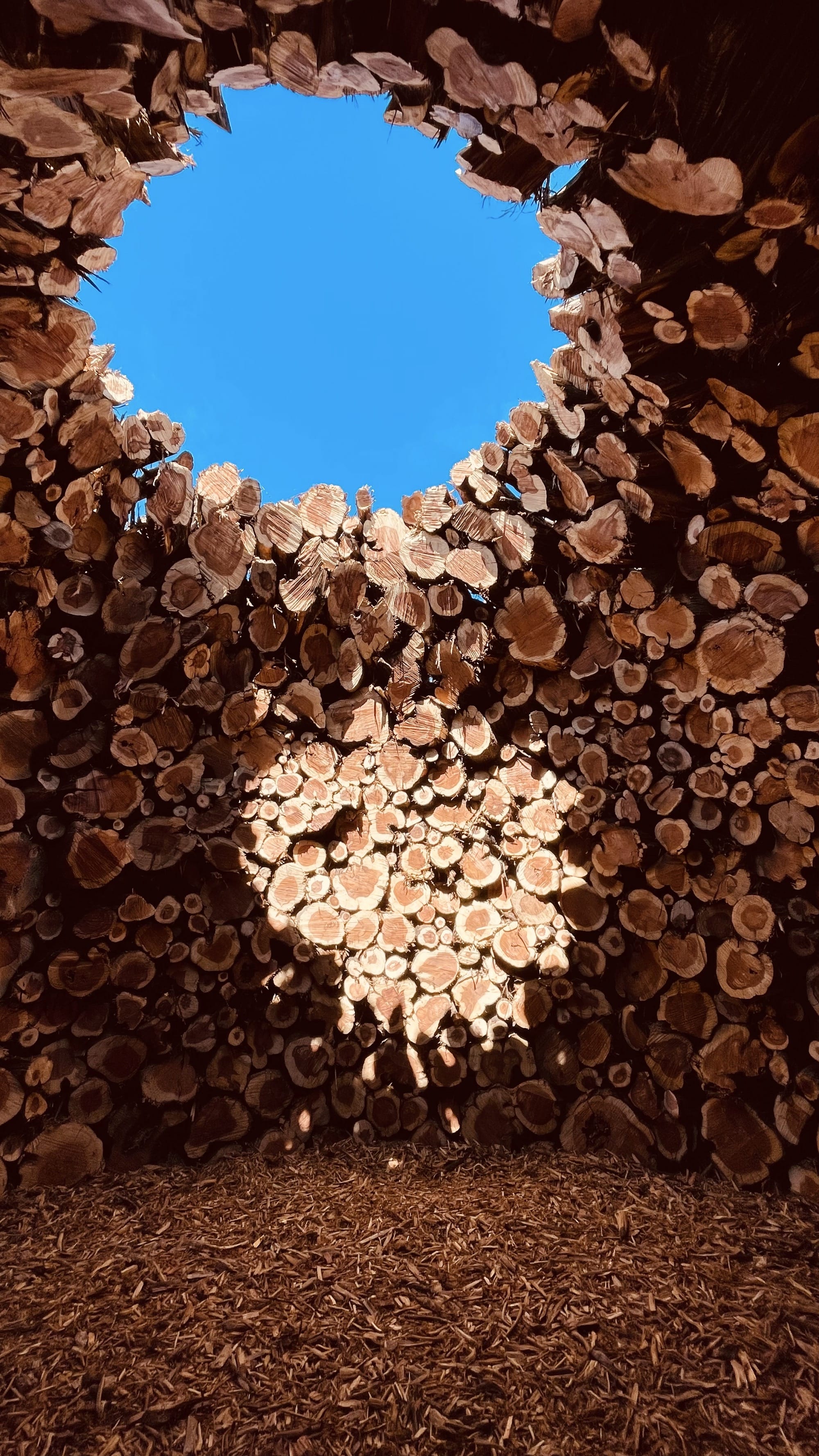stacked logs form an opening in a structure by nomad studi