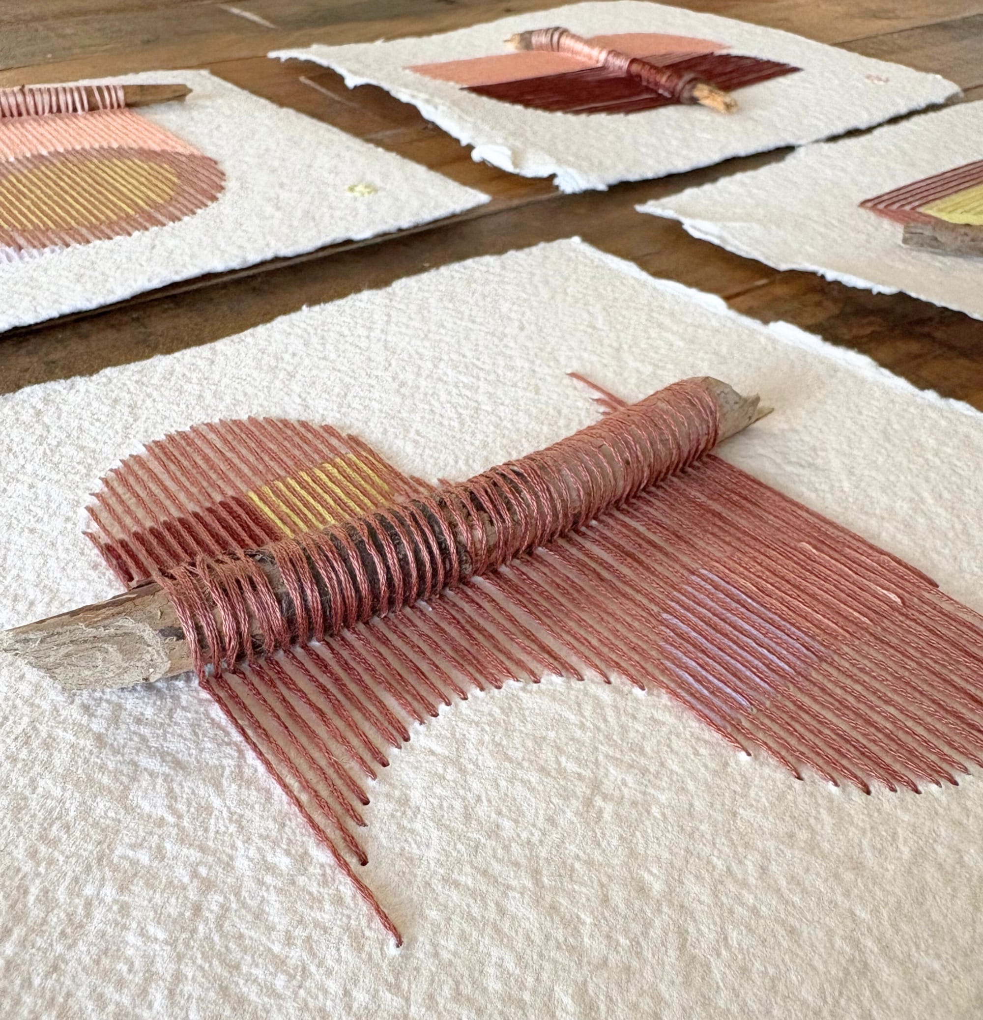 details of four paper artworks by Natalie Ciccoricco featuring handmade paper and thread wound around found twigs